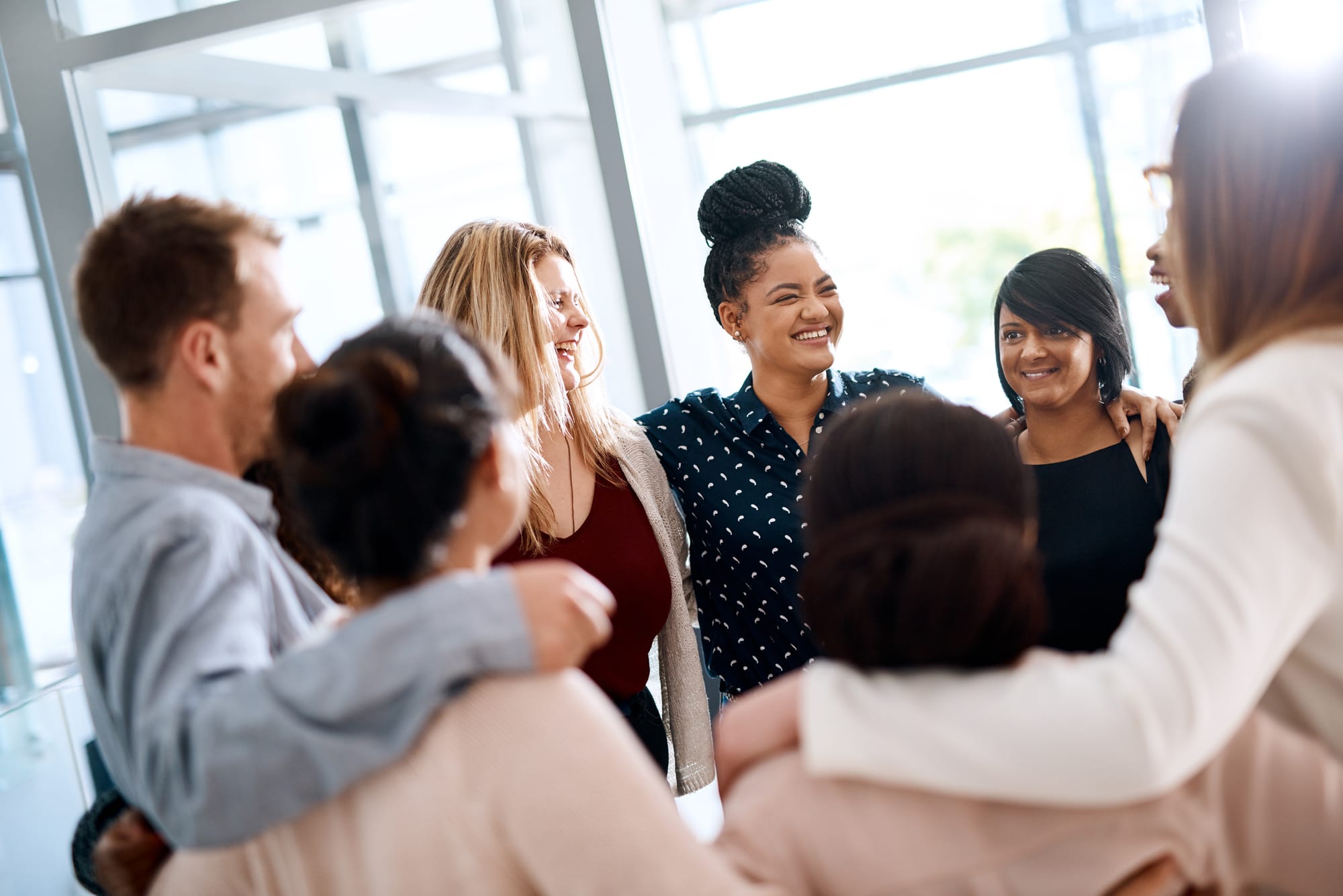 A group of colleagues standing together, arms around each other, laughing